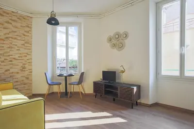 a living room with a tv and a table and chairs at Studio Nid Doré - Welkeys in Cannes