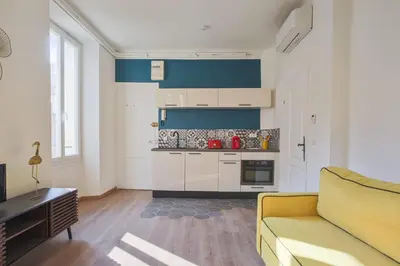 a living room with a yellow couch and a kitchen at Studio Nid Doré - Welkeys in Cannes