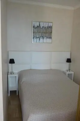 a bedroom with a bed and two tables with lamps at Cozy cocoon with balcony close to the sea in Cannes