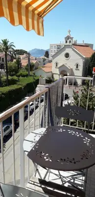 a table and chair sitting on a balcony with an umbrella at Joli appartement vue sur mer in Cannes