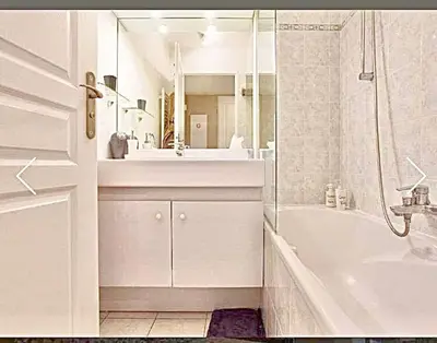 a white bathroom with a tub and a sink at Appartement Canne 1 chambre - 52C in Cannes