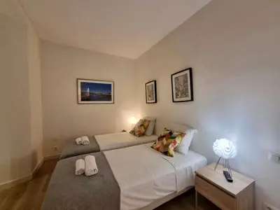 a bedroom with two beds and a table with a lamp at CLEMENCEAU Plage Palais Cannes in Cannes
