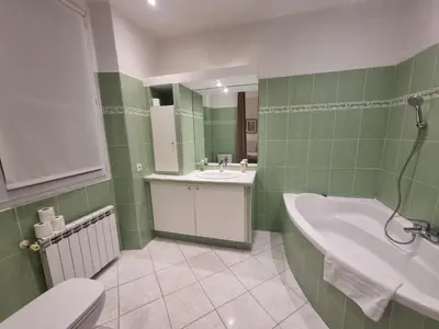 a green and white bathroom with a tub and a sink at CLEMENCEAU Plage Palais Cannes in Cannes