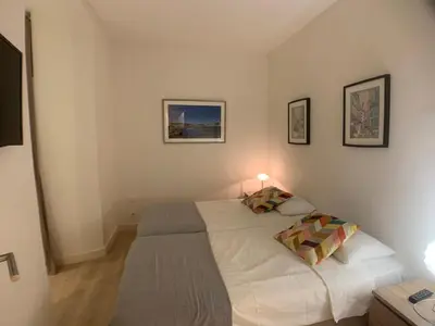a small bedroom with a bed and a table at CLEMENCEAU Plage Palais Cannes in Cannes