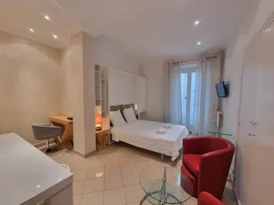 a bedroom with a bed and a red chair at Appartement Commandant André in Cannes