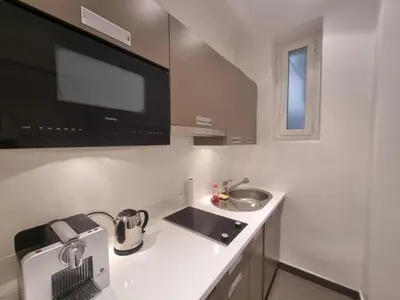a white kitchen with a sink and a microwave at Appartement Commandant André in Cannes