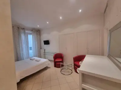 a bedroom with a bed and two red chairs at Appartement Commandant André in Cannes