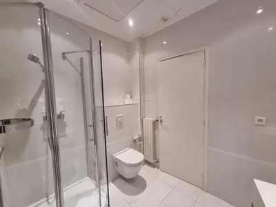 a white bathroom with a shower and a toilet at Appartement Commandant André in Cannes