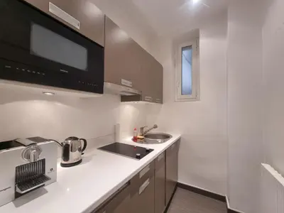 a white kitchen with a sink and a microwave at Appartement Commandant André in Cannes