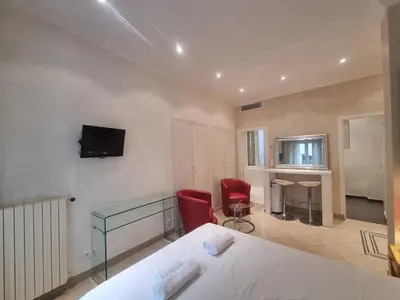 a bedroom with a bed and a desk and a television at Appartement Commandant André in Cannes