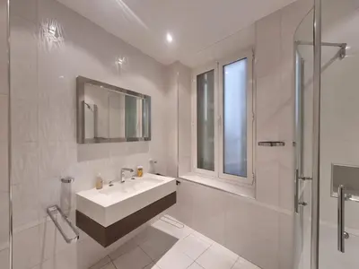 a white bathroom with a sink and a shower at Appartement Commandant André in Cannes