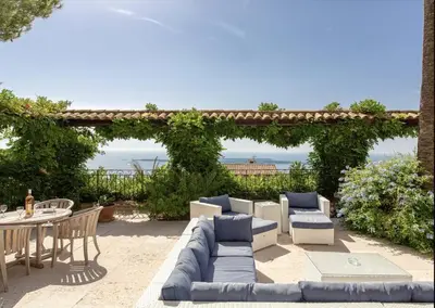 a patio with a couch and chairs and a table at LE CASTEL ROSE Super Cannes, face aux Îles de Lérins in Vallauris