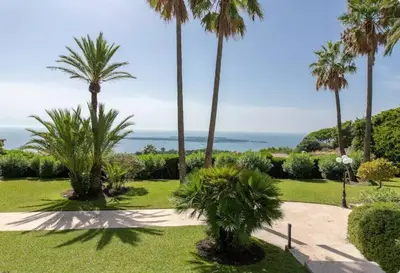 a park with palm trees and the ocean in the background at LE CASTEL ROSE Super Cannes, face aux Îles de Lérins in Vallauris