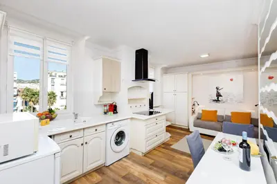 a kitchen with white cabinets and a living room at Dolce Vita YourHostHelper in Cannes