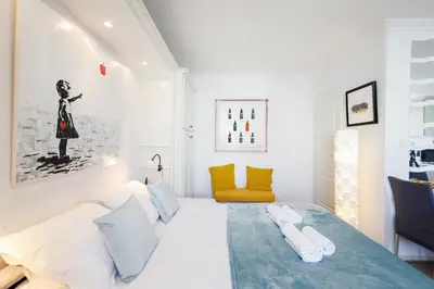 a bedroom with a large white bed and a yellow chair at Dolce Vita YourHostHelper in Cannes