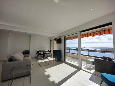 a living room with a couch and a table with a view at Cannes Vue mer T2 61m²+ parking in Cannes