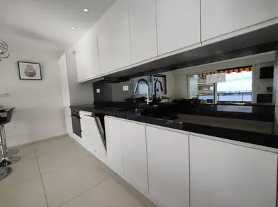 a kitchen with white cabinets and black counter tops at Cannes Vue mer T2 61m²+ parking in Cannes