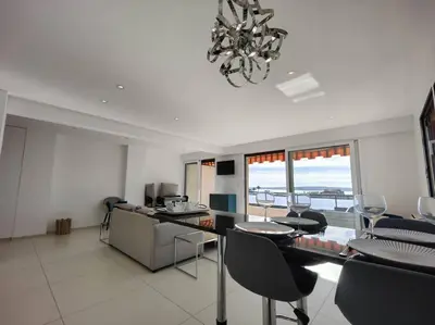 a living room with a table and chairs and a chandelier at Cannes Vue mer T2 61m²+ parking in Cannes