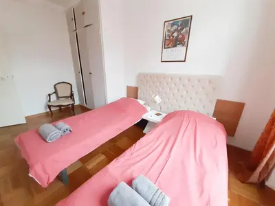 two beds in a room with pink sheets and a chair at Gloria in Cannes