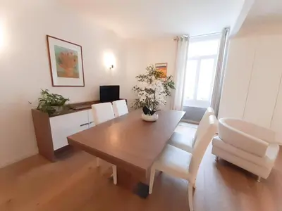 a dining room with a wooden table and white chairs at Gloria in Cannes