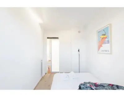 a white room with a bed and a picture on the wall at Bright 2 Bed Apt in Cannes, 10 min to Palais in Cannes