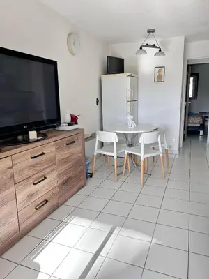 a living room with a television and a table with chairs at Front de mer, 8min du Palais des Festivals in Cannes