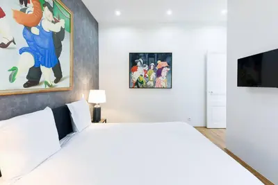 a bedroom with a white bed and a painting on the wall at 3 DAUMAS - Superbe appartement 2 chambres hyper centre Cannes in Cannes