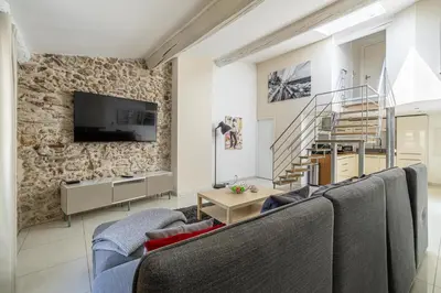 a living room with couches and a stone wall at MEY T3 - Magnifique LOFT 3 pièces à 50m du vieux port et des plages in Cannes
