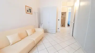 a white living room with a couch and a hallway at Mimosa 1 in Cannes