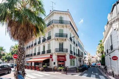 a tall white building on a city street with a palm tree at Mimosa 1 in Cannes