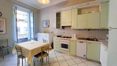 a kitchen with white cabinets and a table with a table cloth at Mimosa 2 in Cannes
