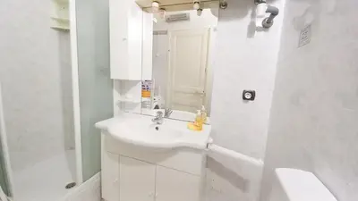 a white bathroom with a sink and a mirror at Mimosa 2 in Cannes