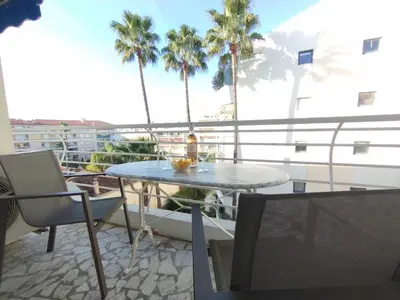 a table and chairs on a balcony with palm trees at Cannes Pointe Croisette T2 plage 2min à pieds 46m2 in Cannes