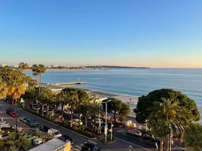 an aerial view of a beach with cars and palm trees at Stunning 2 bedroom flat with sea view on Croisette in Cannes