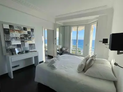 a white bedroom with a large bed and a desk at Stunning 2 bedroom flat with sea view on Croisette in Cannes