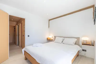 a white bedroom with a large bed and a mirror at LB Vacation Rentals I A short Stroll to Palais, Beach, Terrace & Seaview in Cannes