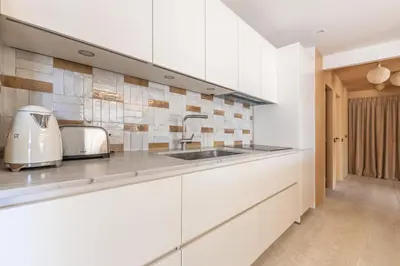 a kitchen with white cabinets and a sink at LB Vacation Rentals I A short Stroll to Palais, Beach, Terrace & Seaview in Cannes