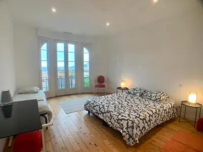 a bedroom with a bed and two chairs and windows at Appartement Grasse Toit Terrasse in Cannes
