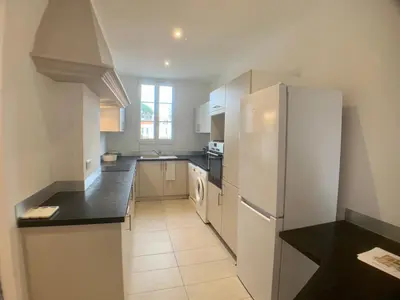 a kitchen with a white refrigerator and black counter tops at Appartement Grasse Toit Terrasse in Cannes