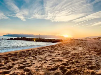 a beach with the sun setting in the background at Fiorella's Cannes Oasis in Cannes