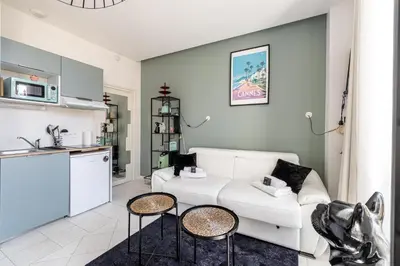 a living room with a white couch and a kitchen at PRIVATE - Small studio for two at 5 minutes from Croisette in Cannes