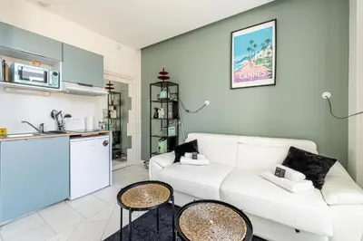 a living room with a white couch and a kitchen at PRIVATE - Small studio for two at 5 minutes from Croisette in Cannes