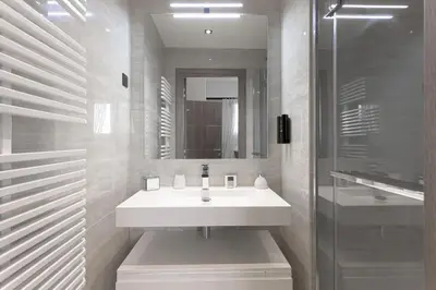 a white bathroom with a sink and a shower at Palais Des Iles - La Croisette by Halldis in Cannes