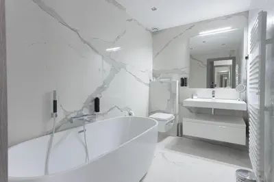 a white bathroom with a tub and a sink at Palais Des Iles - La Croisette by Halldis in Cannes