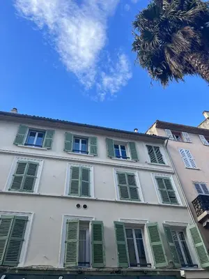 a white building with green shutters and a palm tree at Greyson apartment 3 from Palais by Welcome to Cannes in Cannes