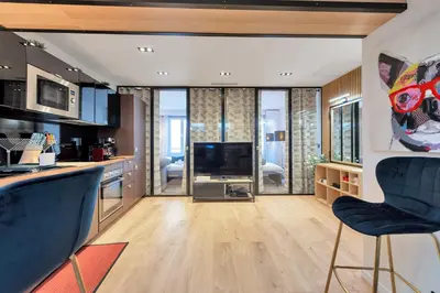 a living room with a kitchen with a television at LE NAPOLEON chic et moderne, l'endroit parfait au cœur de la Banane in Cannes