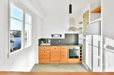 a kitchen with wooden cabinets and a large window at LE MARINE vue mer avec joli terrasse, un rêve pour les couples in Cannes