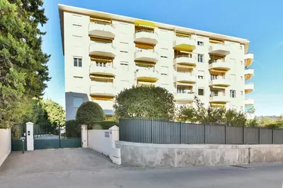 a white building with a fence in front of it at LE MARINE vue mer avec joli terrasse, un rêve pour les couples in Cannes