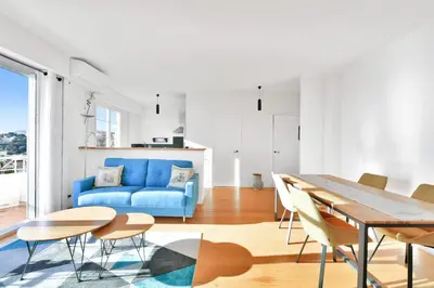 a living room with a blue couch and a table at LE MARINE vue mer avec joli terrasse, un rêve pour les couples in Cannes