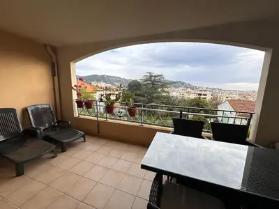 a balcony with chairs and a view of a city at 2 bedroom apartment with a pool in the heart of Cannes easy walk to the main beach on La Croisette - 2191 in Cannes